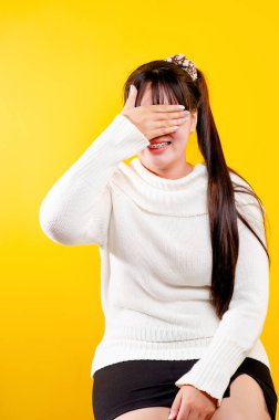 Asyalı kız o neşeli, eğlenceli, parlak gülümseme. Sevgi dolu gözlerin ifadesi iyi bir yaşam ve iş yerinde mutluluk, rahatlama, sarı bir arka plana karşı.