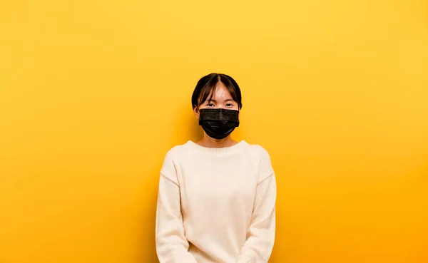 Asian woman wearing a mask Corona virus prevention rest in quarantine The social and emotional distance concept you\'re thinking of going. girl in a medical mask yellow scene studio photography