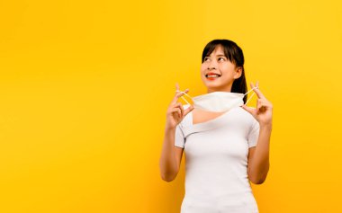 Diğerlerini COVID-19 Corona 'dan korumak ve mutlu bir şekilde gülümsemek için anti-virüs maskesi takan Asyalı kadın..