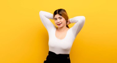 Mutlu ve rahat Asyalı kadın sarı arka planda mutlu bir şekilde gülümsüyor.