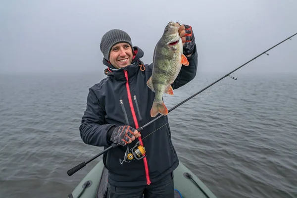 快乐的渔夫用钓具把大鱼抱在船上 在野生湖中成功捕鱼 — 图库照片