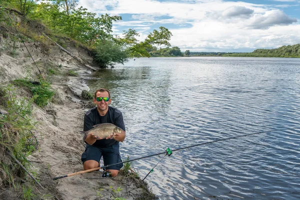 餌釣りだ 大きな鯛を手にした漁師が天然の川の岸に取り組む — ストック写真