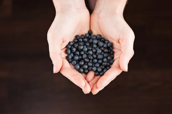 Woman with handful billberies on dark background — Stock Photo, Image