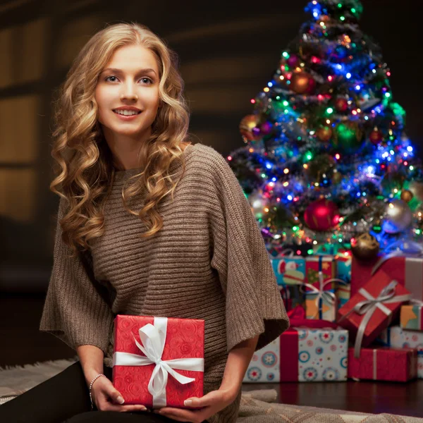 Young smiling woman holding red christmas gift — Stock Photo, Image