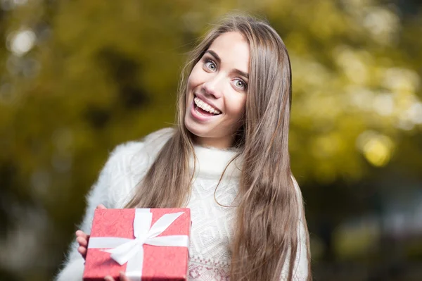 Attractive young woman holding red present — Stock Photo, Image