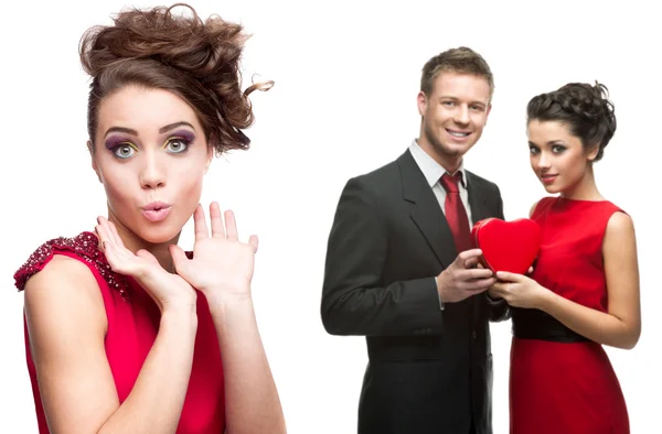 Young surprised woman and couple holding red heart on white back — Stock Photo, Image