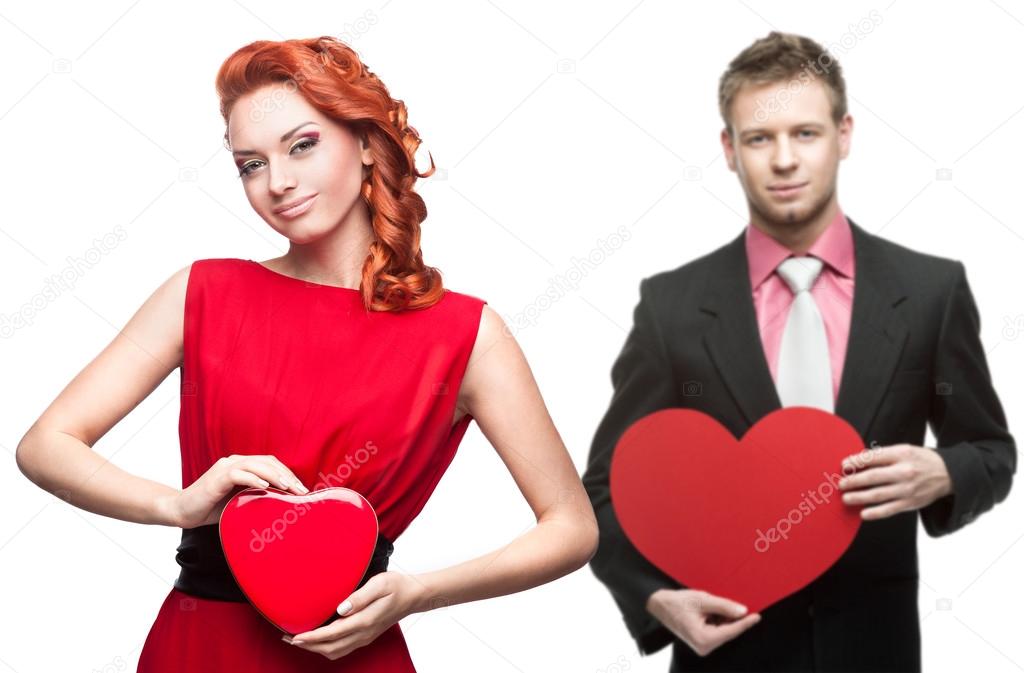 young cheerful woman and handsome man holding red heart on white