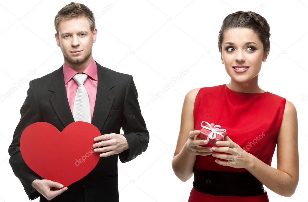 Young handsome man holding red heart and smiling woman holding g