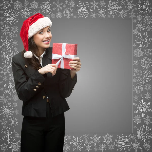 Geschäftsfrau mit Weihnachtsmann-Hut hält Geschenk in der Hand — Stockfoto