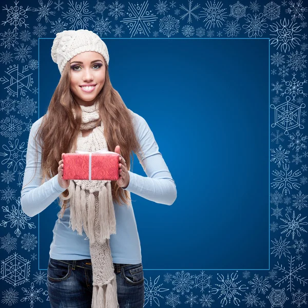 Happy young woman holding gift over winter background — Stock Photo, Image