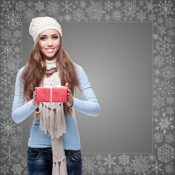 Happy young woman holding gift over winter background — Stock Photo, Image