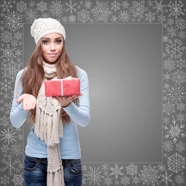 Happy young woman holding gift over winter background — Stock Photo, Image