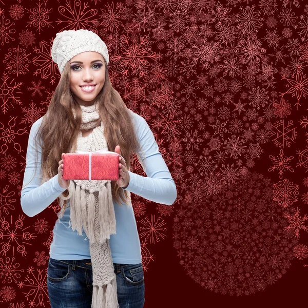 Happy young woman holding gift over winter background — Stock Photo, Image