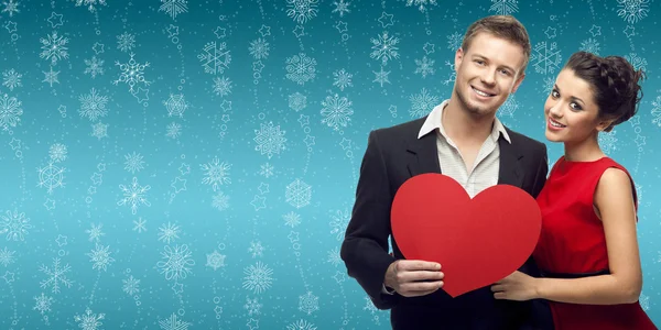 Young couple holding heart over winter background — Stock Photo, Image