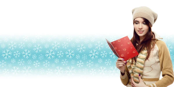 Woman reading christmas postcard over winter snowflakes backgrou — Stock Photo, Image