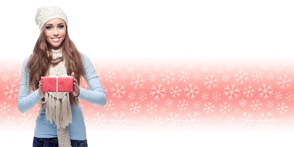 Glückliche junge Frau hält Geschenk über winterlichem Hintergrund — Stockfoto