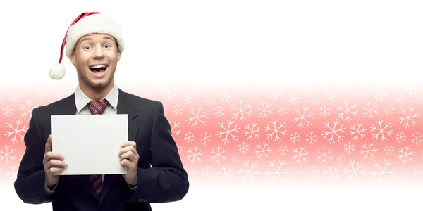 Young business man in santa hat holding sign over winter backgro — Stock Photo, Image