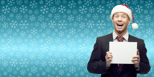 Young business man in santa hat holding sign over winter backgro — Stock Photo, Image