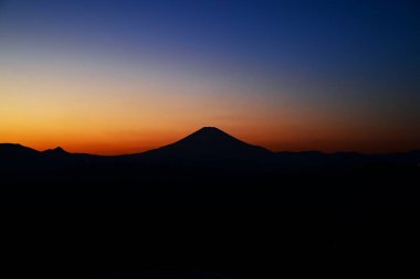 Sunset Dağı 'nın günbatımı silueti. Fuji, Japonya 'nın en güzel ve büyüleyici manzaralarından biridir. Güneş battıkça, gökyüzünün rengi derinleşiyor ve Mt. Fuji siyah bir siluet gibi öne çıkıyor..
