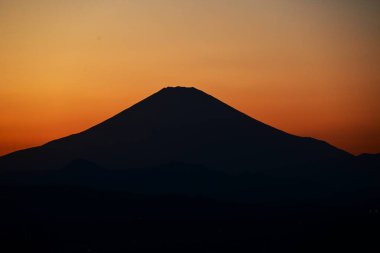 Sunset Dağı 'nın günbatımı silueti. Fuji, Japonya 'nın en güzel ve büyüleyici manzaralarından biridir. Güneş battıkça, gökyüzünün rengi derinleşiyor ve Mt. Fuji siyah bir siluet gibi öne çıkıyor..