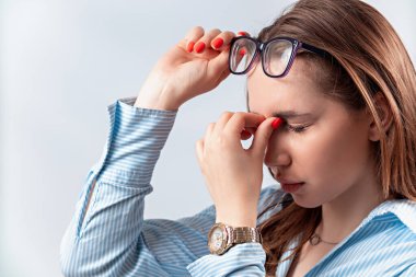 Gözlerini ovuşturan genç bir kadın beyaz arka planda izole edilmiş.