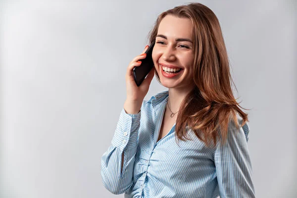 Mavi gömlekli güzel bir kız telefonda beyaz arka planda konuşuyor. — Stok fotoğraf