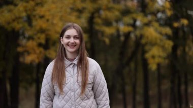 Günbatımında gülen ve saçlarına dokunan güzel bir kadın. Sıcak güneş ışığı, doğal güzellik, yumuşak duygular, huzurlu bir an..