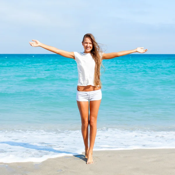 女孩站在海滩上，伸开双臂 — 图库照片