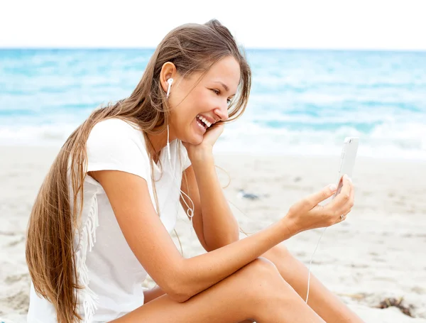 Flickan med mobiltelefon enheten på stranden — Stockfoto