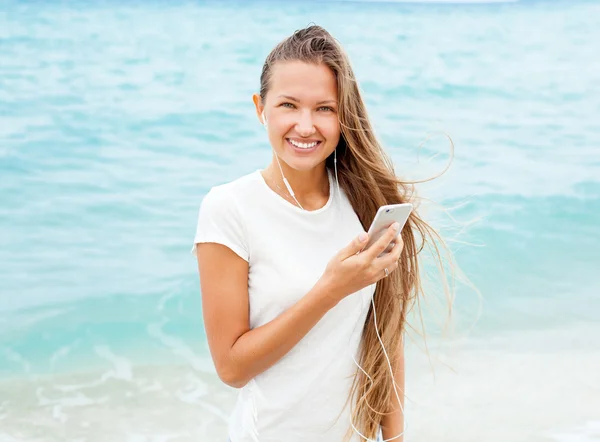 Flickan med mobiltelefon enheten på stranden — Stockfoto