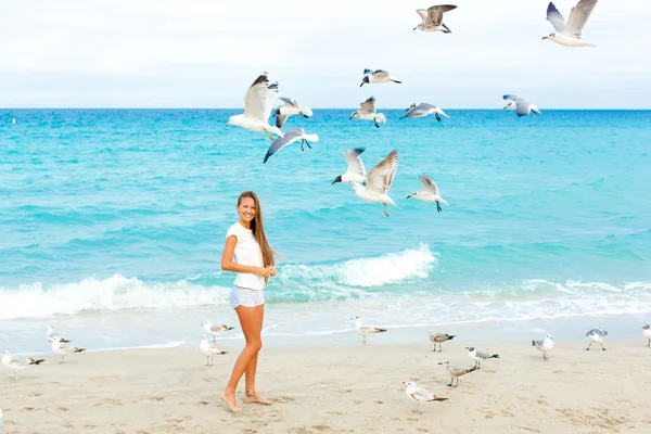 Girl on the beach feeding seagulls — Stock Photo, Image