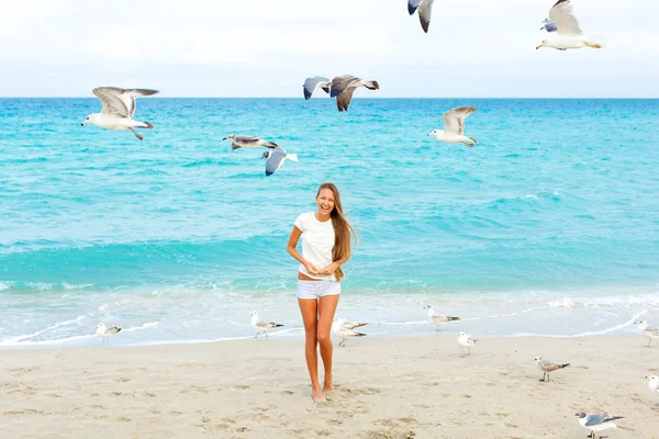 Flicka på stranden mata måsarna — Stockfoto