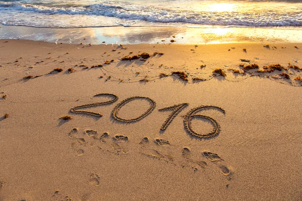 Año 2016 escrito en arena al atardecer — Foto de Stock