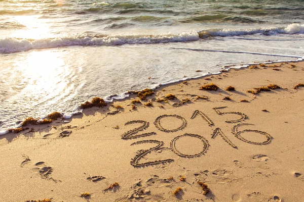 2015 и 2016 знаки на пляжном песке — стоковое фото