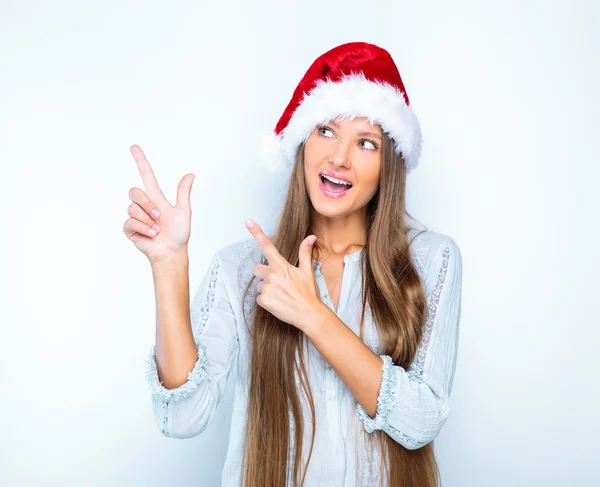 Girl in santa hat pointing at something — Stockfoto