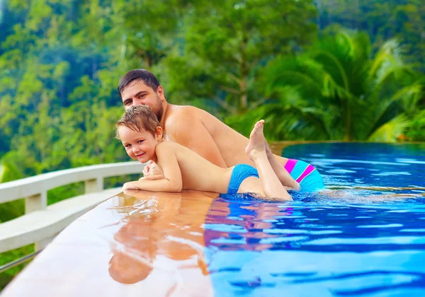 Feliz padre e hijo relajándose en la piscina infinita en la isla tropical — Foto de Stock