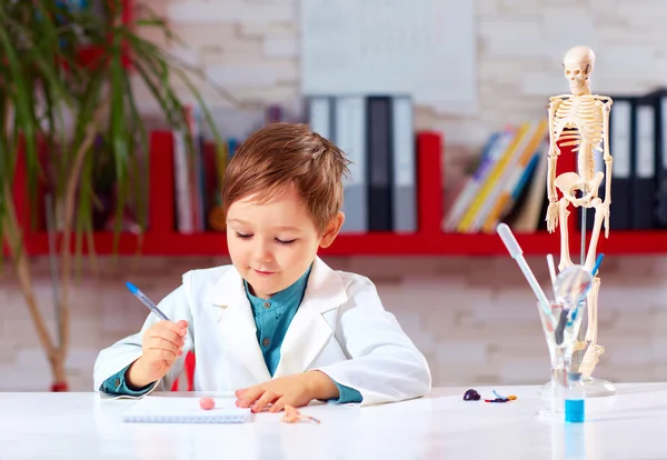 Милый маленький доктор пишет заметки в лаборатории — стоковое фото