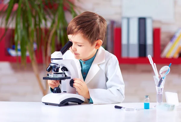 Le jeune enfant mène une expérience avec un microscope dans un laboratoire scolaire — Photo
