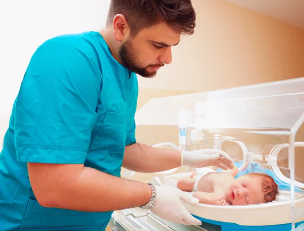 Fiatal felnőtt férfi, ügyelve az újszülött, a csecsemő inkubátor — Stock Fotó