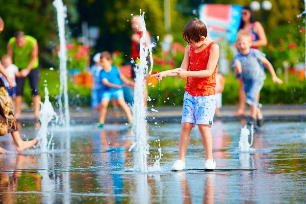 Podekscytowany chłopiec zabawy między wodą rozpryskową, fontanny. SUMM — Zdjęcie stockowe