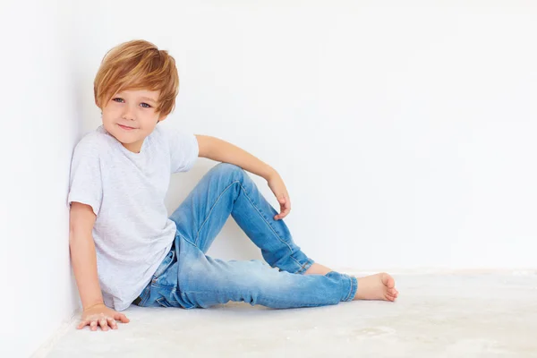 Красивый молодой мальчик, сидит рядом с белой стеной — стоковое фото
