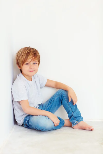 Beau jeune garçon, enfant assis près du mur blanc — Photo