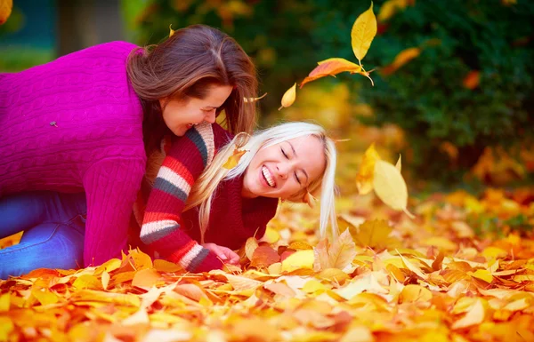 Glada tjejer, vänner har kul bland nedfallna löv på hösten park — Stockfoto