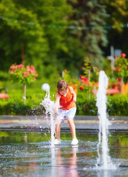 Chico excitado divirtiéndose entre chorros de agua, en la fuente. Verano en la ciudad —  Fotos de Stock