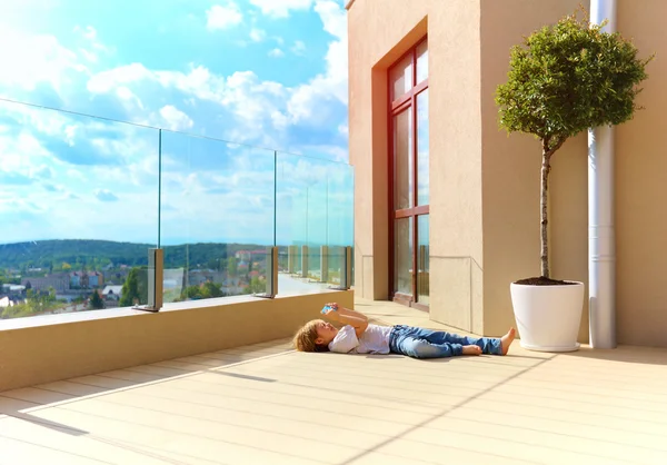 Молодий хлопчик розслабляється на терасі, на верхньому поверсі — стокове фото