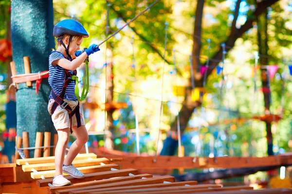 Ung pojke passerar kabel vägen högt bland träden, extrem sport i äventyrsparken — Stockfoto