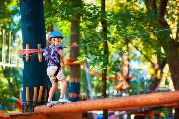 Jonge jongen passeren het kabeltracé hoog onder bomen, extreme sport in avonturenpark — Stockfoto