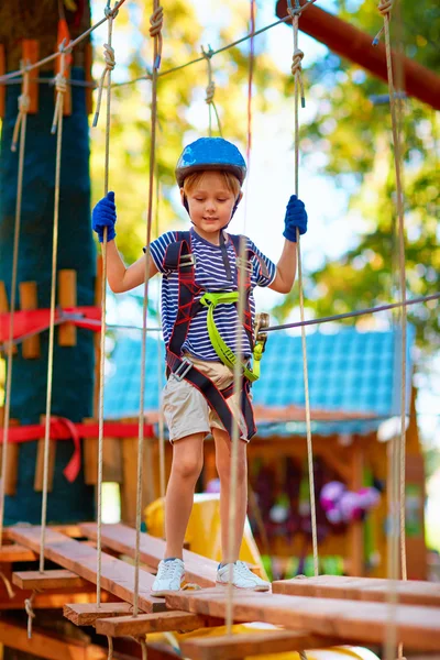 Jonge jongen passeren het kabeltracé hoog onder bomen, extreme sport in avonturenpark — Stockfoto