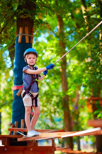 Ung pojke passerar kabel vägen högt bland träden, extrem sport i äventyrsparken — Stockfoto
