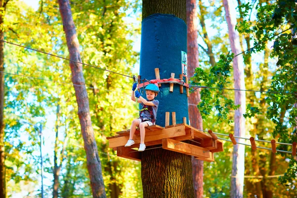 Chico joven pasando la ruta de cable alto entre los árboles, deporte extremo en el parque de aventuras — Foto de Stock